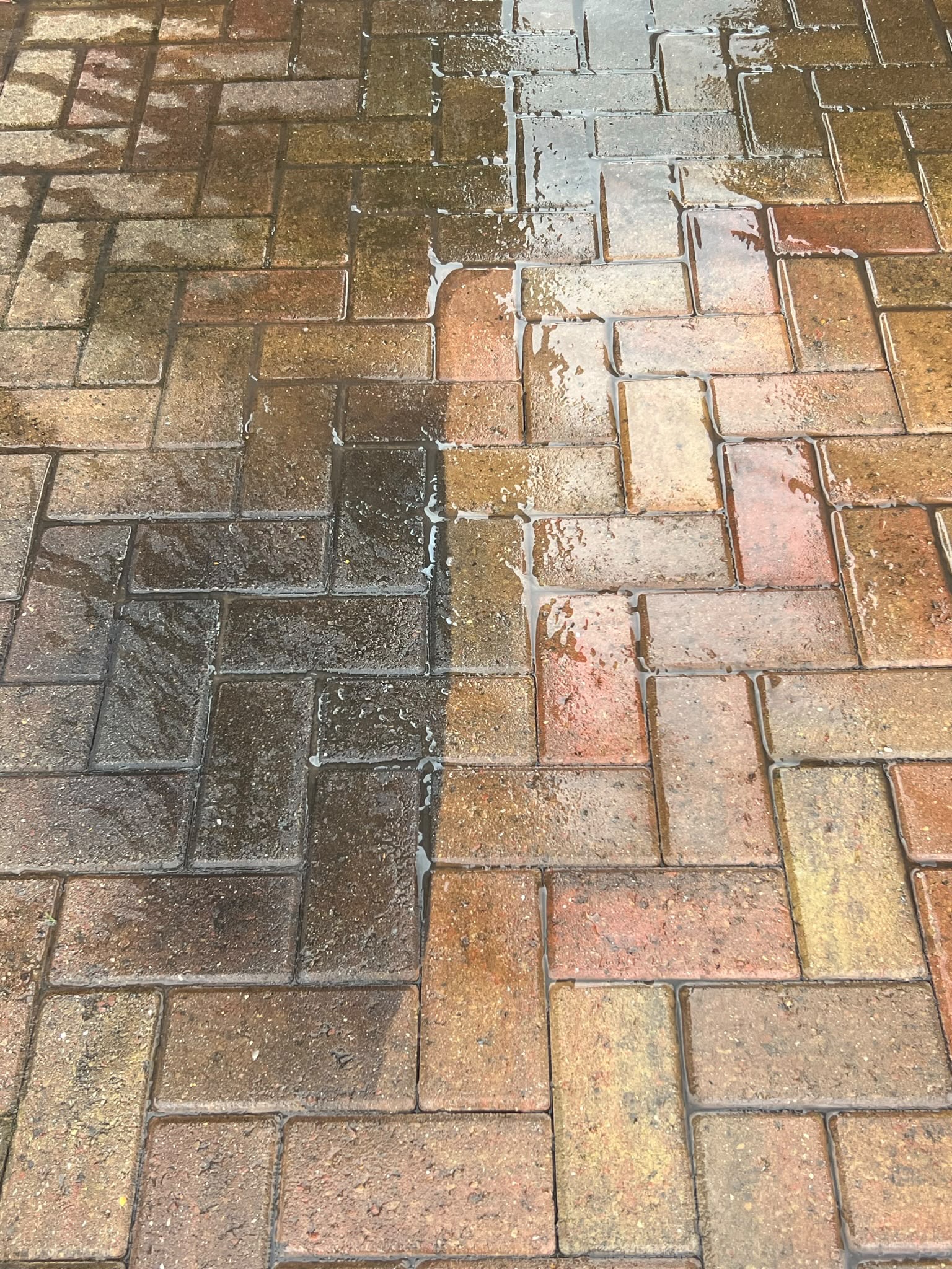 Herringbone block paving split between dirty blackened bricks on the left and freshly cleaned multi-tone bricks on the right